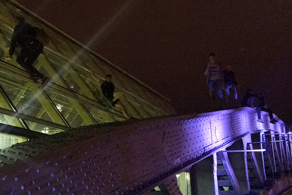 На металлические арки Андреевского моста забирается молодежь, но охрана на это никак не реагирует