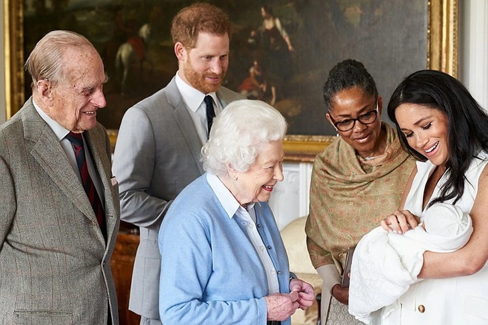 По фото видно, что Елизавета II и ее муж герцог Эдинбургский расплываются в улыбке, глядя на ребенка