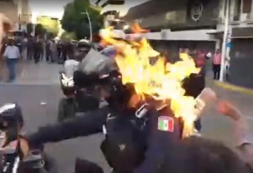 Протестующие мексиканцы подожгли полицейского в ходе беспорядков. Фото: кадр из видео