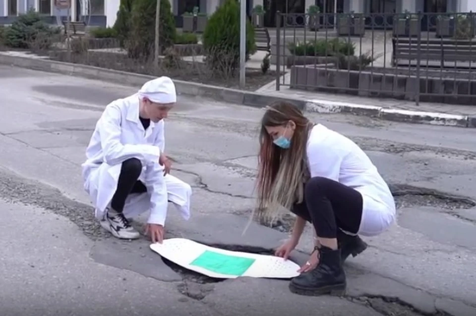 В начале ролика молодые люди в белых халатах «заклеили» дорожную яму огромным лейкопластырем Фото: https://vk.com/my_tgn
