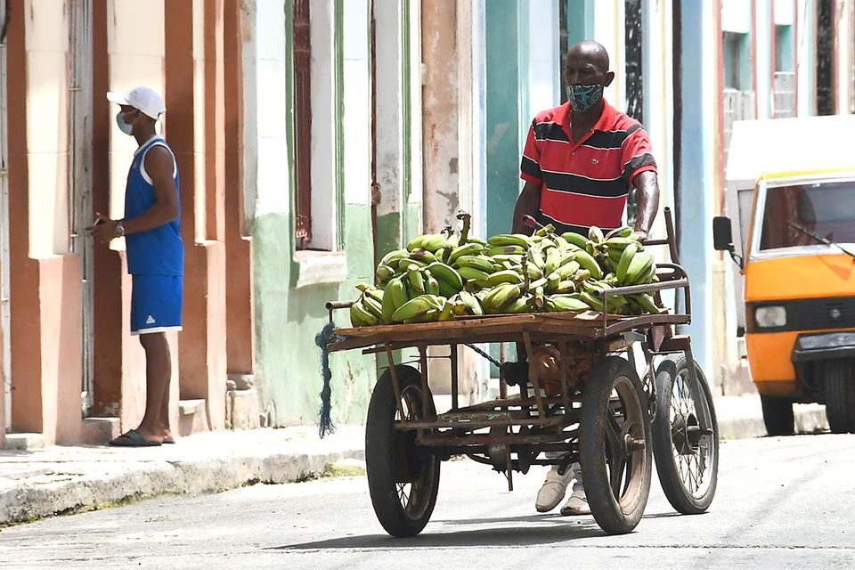 Продавец бананов катит свою тележку по улицам Гаваны, Куба.