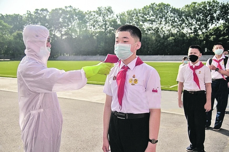 На официальных фото все выглядит прекрасно. Как и эти пионеры в Пхеньяне, которым перед уроками меряют температуру. Фото: KIM WON JIN/AFP via Getty Images
