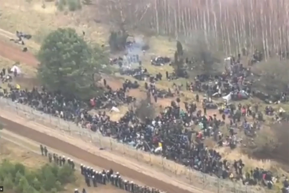 Толпа мигрантов расположилась около заграждения из колючей проволоки на польско-белорусской границе. Фото: кадр из видео Минобороны Польши.