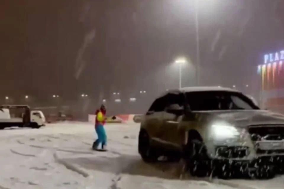 Девушка каталась на сноуборде на парковке у ТРЦ. Фото: скриншот видео/t.me/groupmurmansk