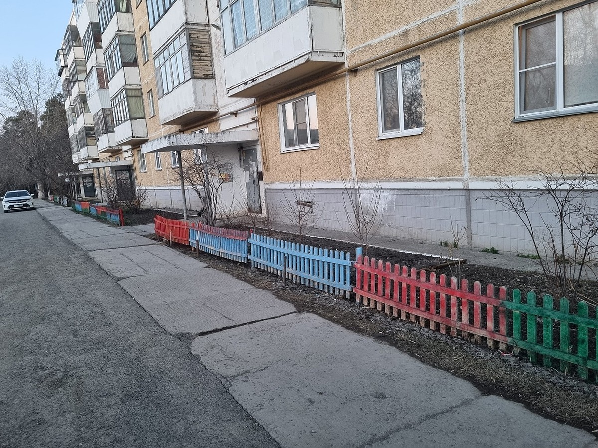 Некто красит красной краской забор вокруг дома