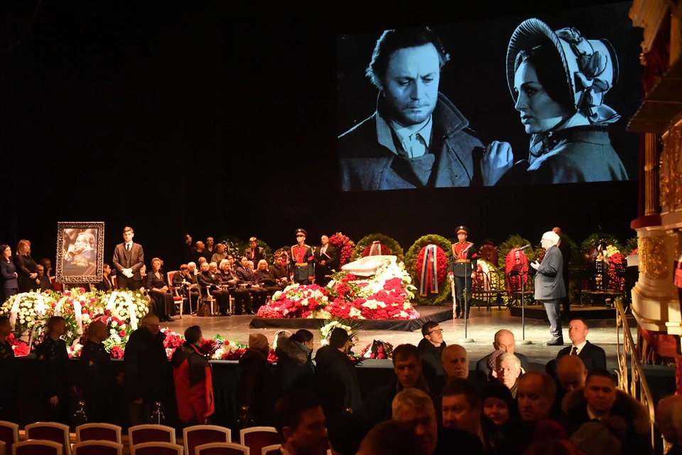 Зрительный зал Исторической сцены заполнен до верхних ярусов. Люди несут цветы к гробу Юрия Соломина, который установлен на сцене в окружении почётного караула.
