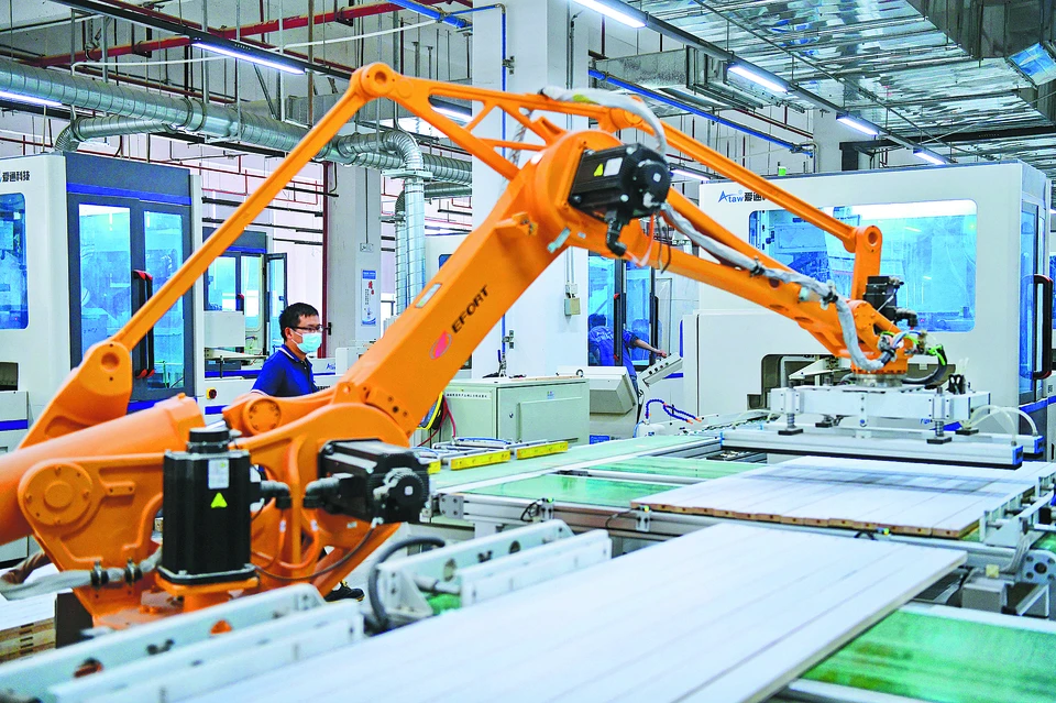 Сотрудник наблюдает за работой умного робота, обрабатывающего детали мебели на производственном предприятии в Ганьчжоу, провинция Цзянси. / ЧЖУ ХАЙПЭН / ДЛЯ CHINA DAILY