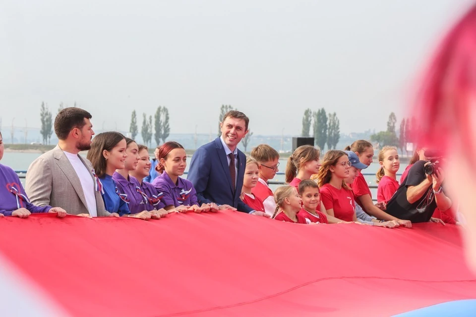 Сергей Петрин держит вместе с молодыми активистами огромный флаг России.
