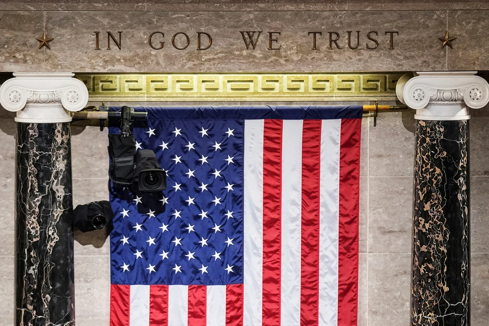 Надпись In God We Trust (На Бога уповаем) выгравирована на камне над флагом США в зале заседаний палаты представителей в Капитолии, Вашингтон. Фото:Sarahbeth Maney/The New York Times/AP