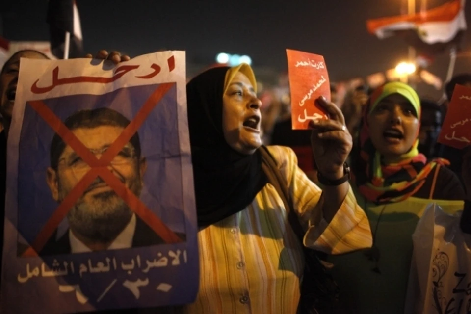 Участники акции размахивают египетскими флагами и плакатами с антиправительственными лозунгами