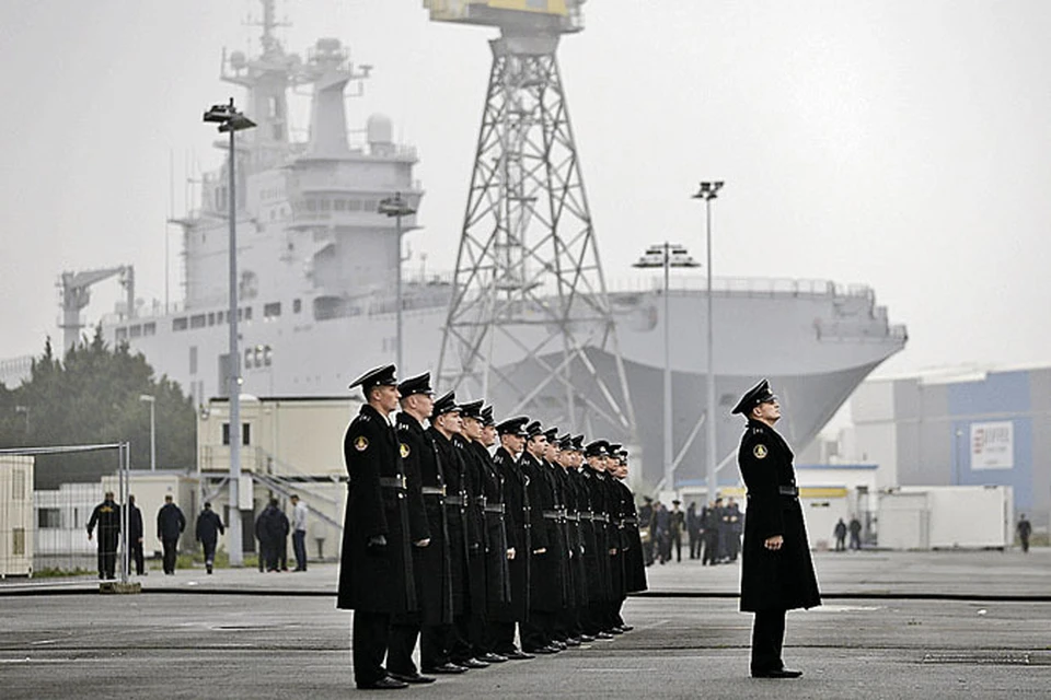 Российские моряки выстроились на ежедневном разводе во Франции. Они по-прежнему готовы принять «Мистраль» (на фото он на заднем плане). Но Париж пока упорствует.